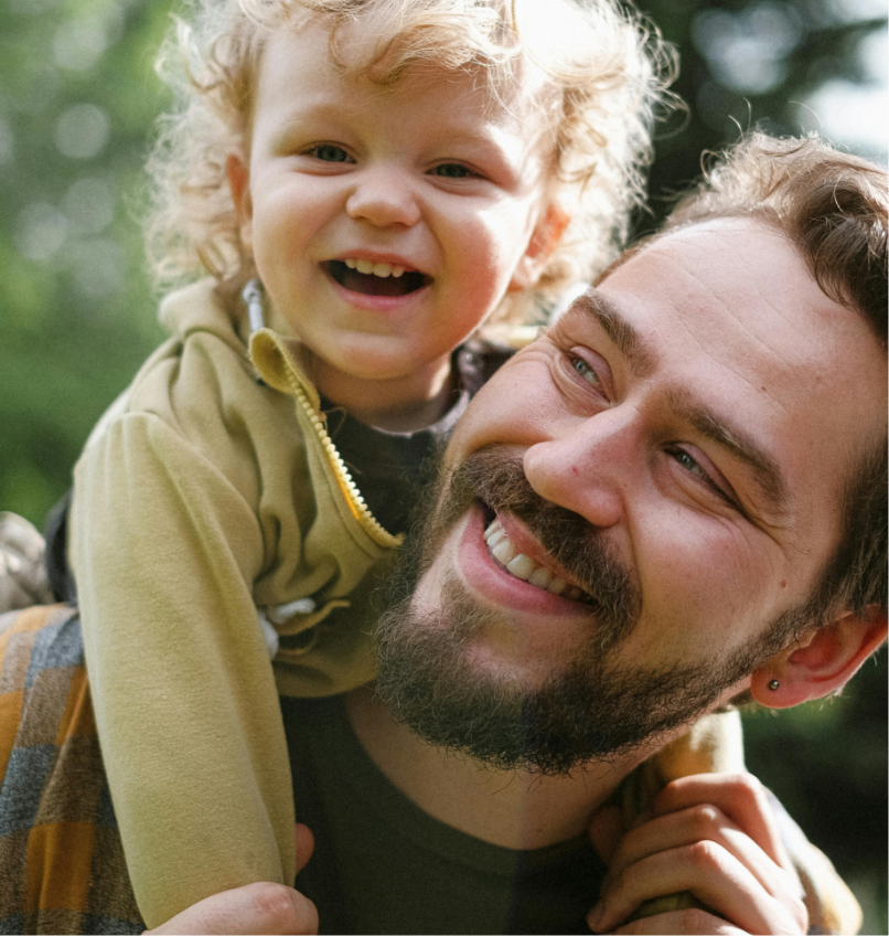 A happy father carrying his smiling son on his shoulders